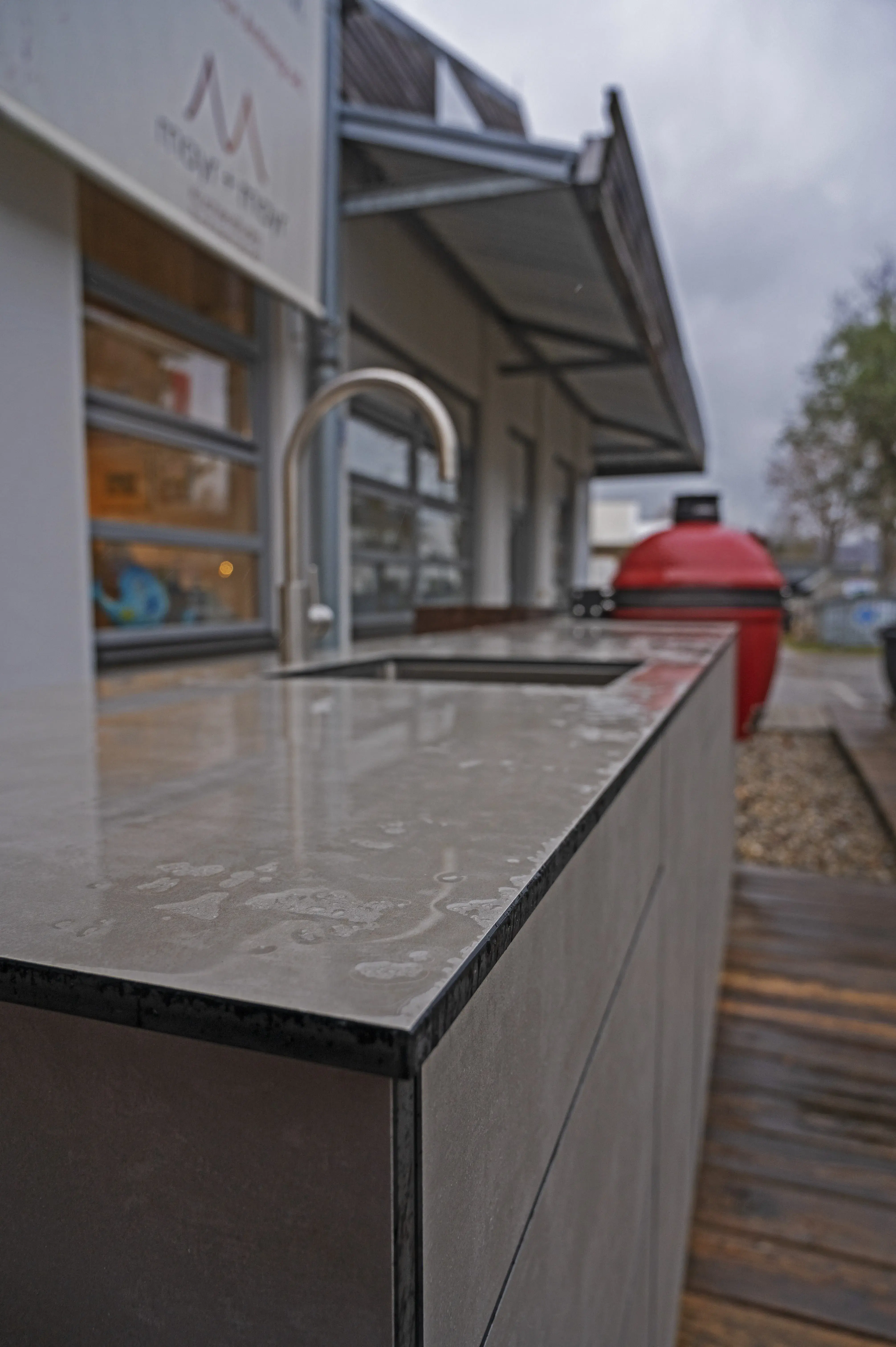 Regennässe auf Outdoor-Küche mit Hauswand und Terrasse im Hintergrund